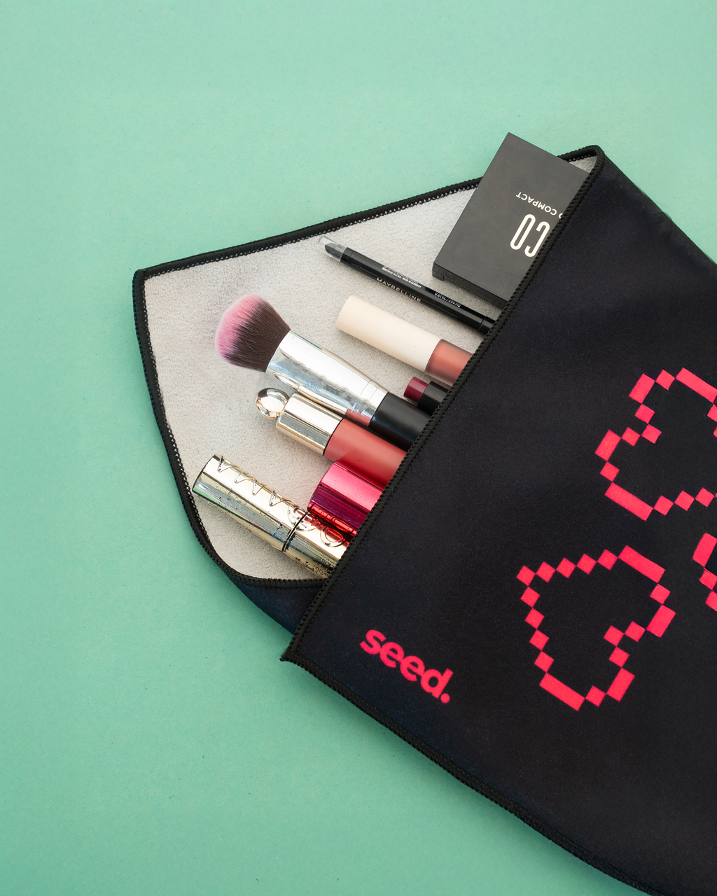 Makeup set with lipsticks, brushes, and a compact mirror in a black pouch on a green background. Hold Up Magic Self Adhesive Wrap Organiser Tell Tale Heart