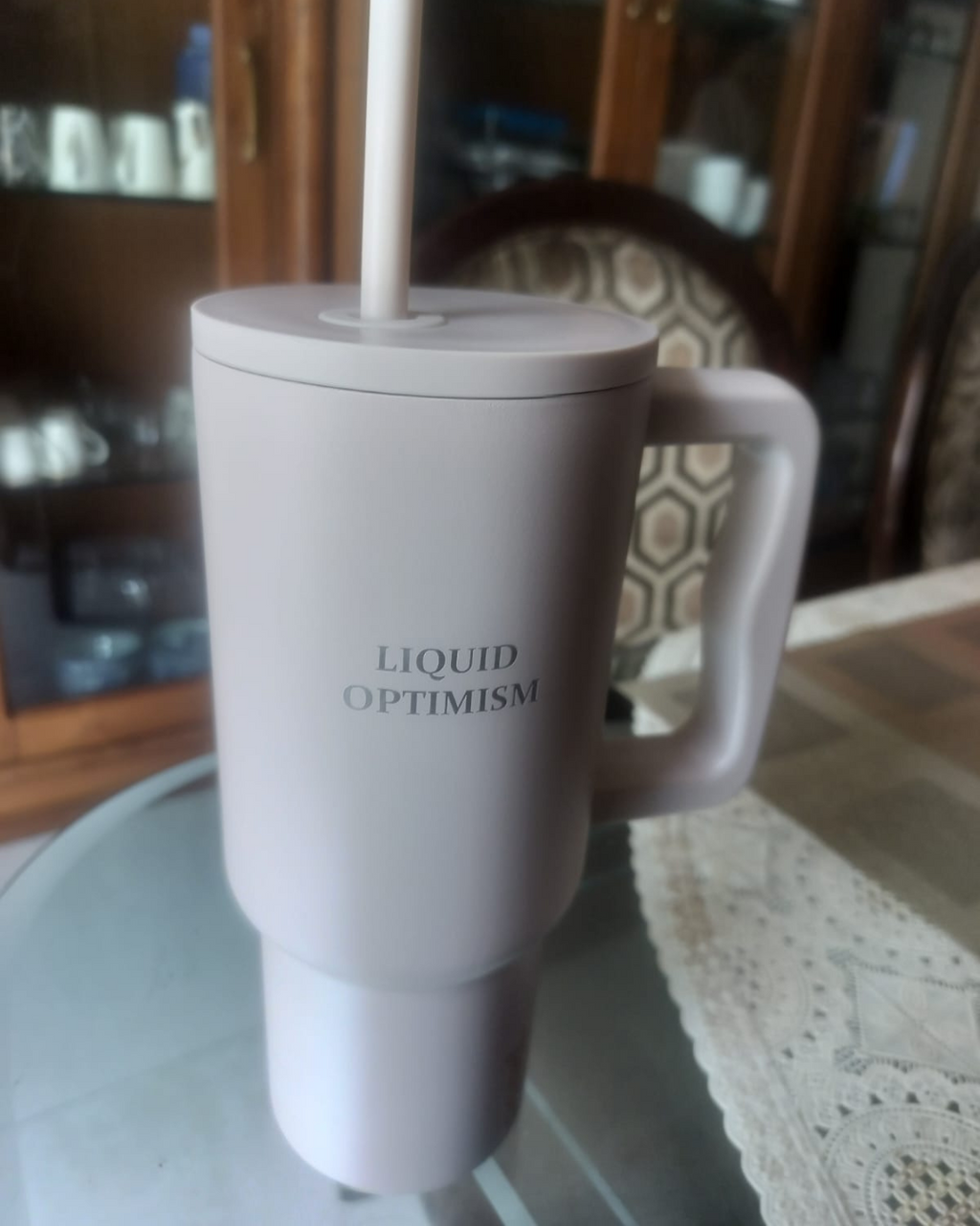 beige mug with 'LIQUID OPTIMISM' text on a glass surface. stainless steel tumbler 900mL milk tea