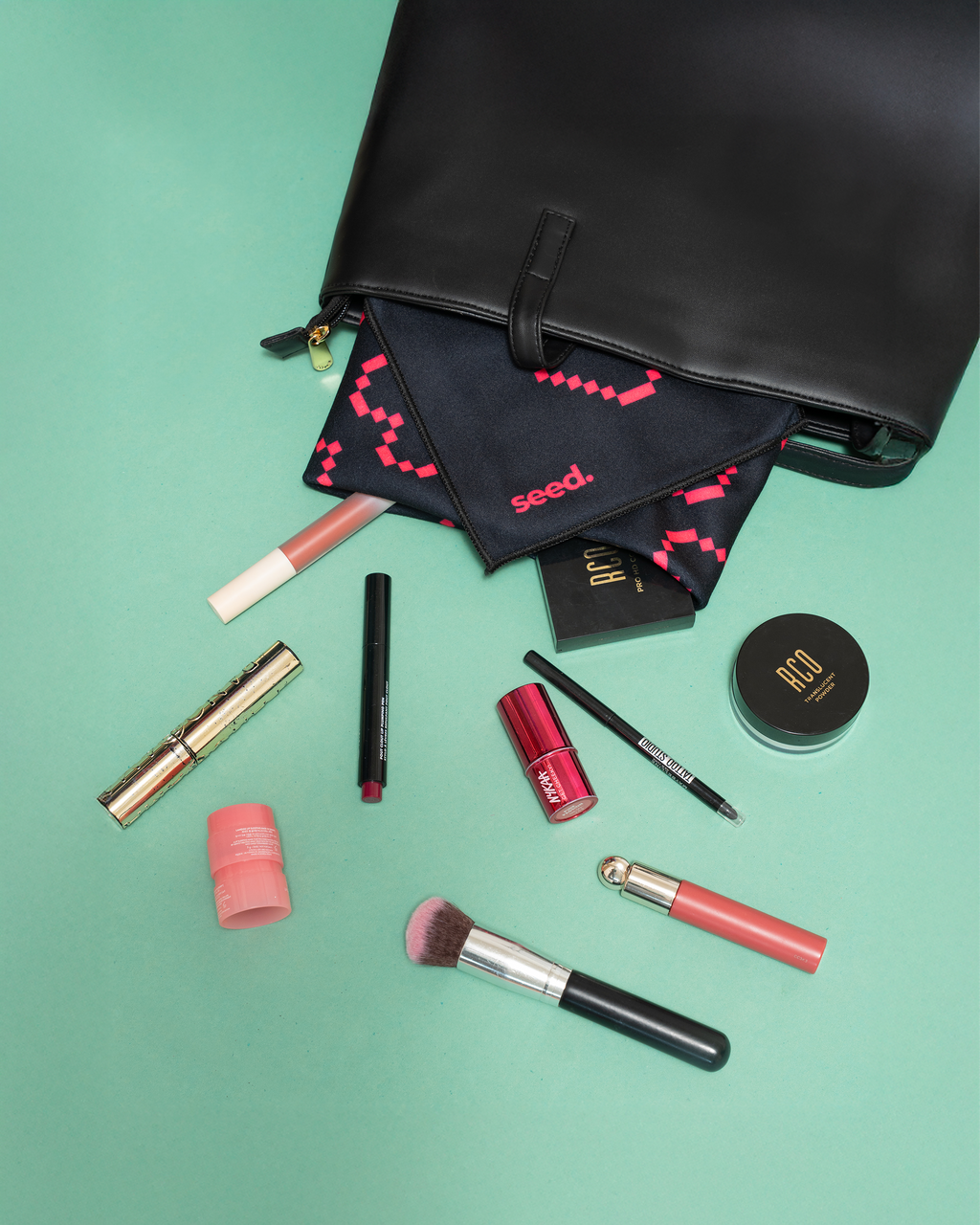 Makeup products including brushes and lipsticks on a green background with a black pouch. Hold Up Magic Self Adhesive Wrap Organiser Tell Tale Heart