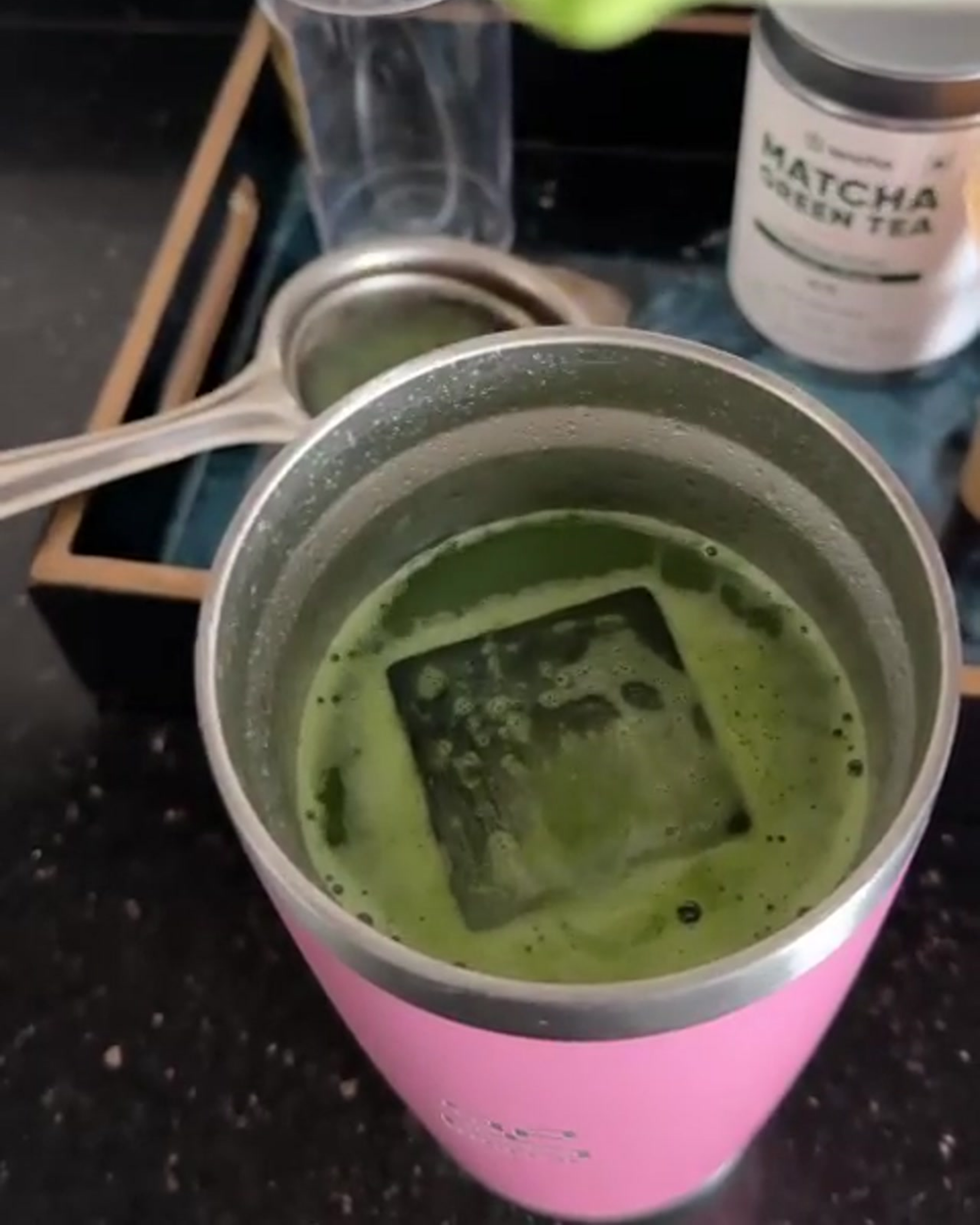 Pink travel mug with chilled matcha green tea and a canister of matcha powder on a dark surface. insulated stainless steel tumbler 600mL baby pink  insulated stainless steel travel coffee mug 600mL 