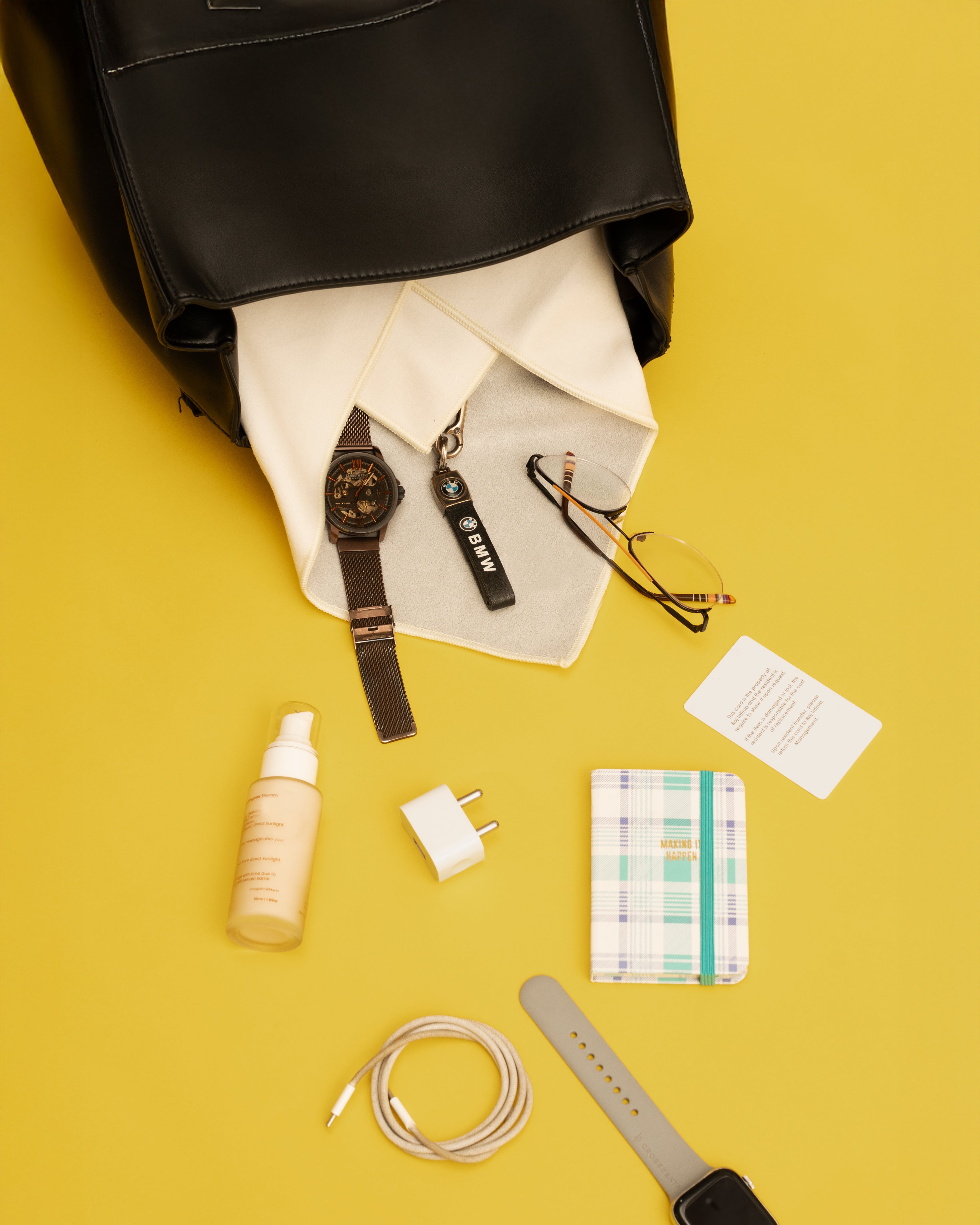 Black backpack with items like a watch, bottle, and notebook on a yellow background Hold Up Magic Self Adhesive Wrap  Organiser Cat In The Bag